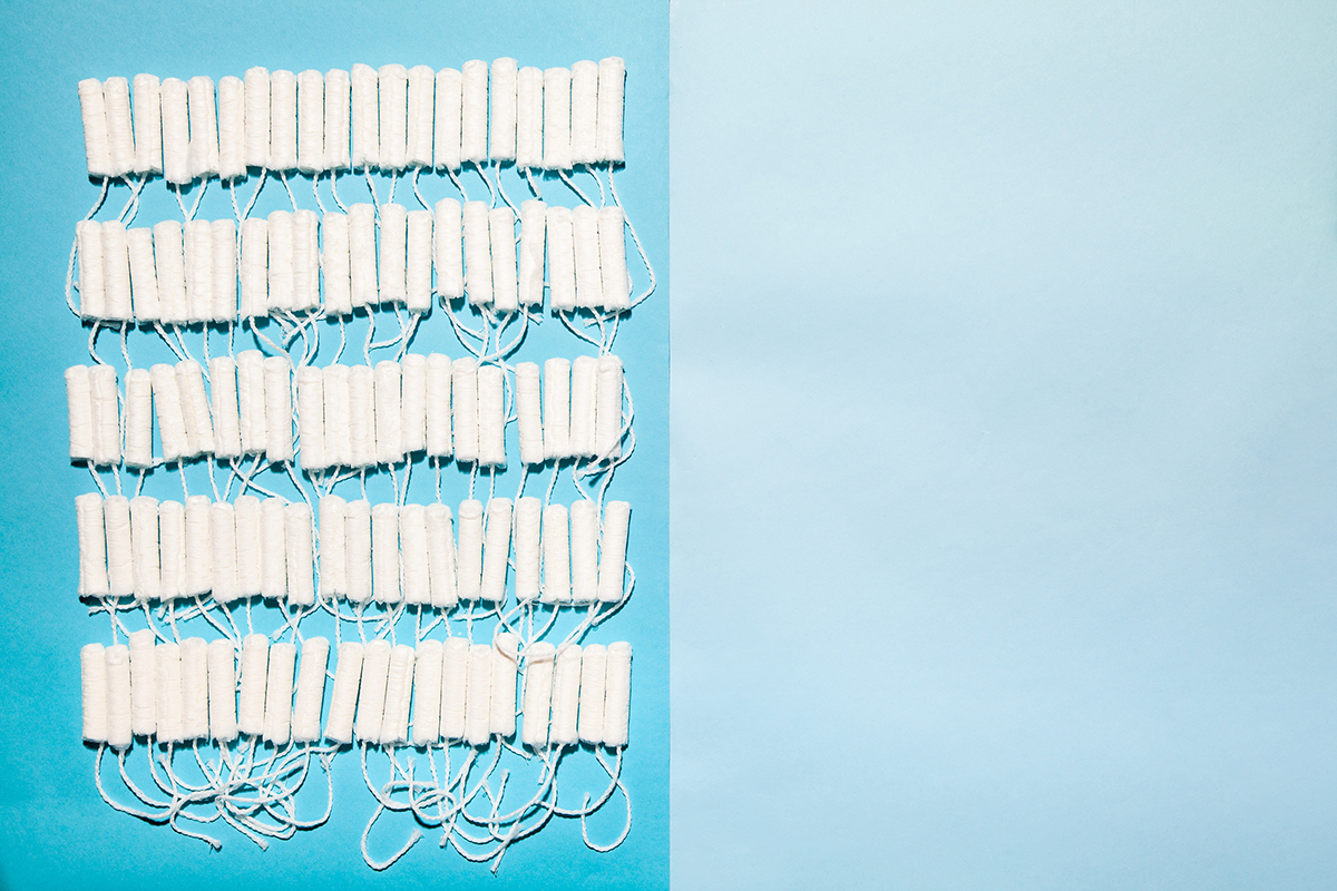 Photograph of 100 tampons on left on medium blue background, and blank light blue background on right