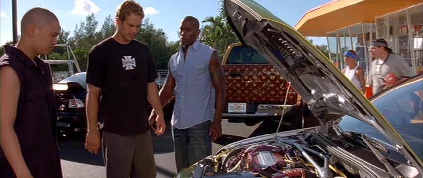 Three men standing in front of a car with an exposed engine