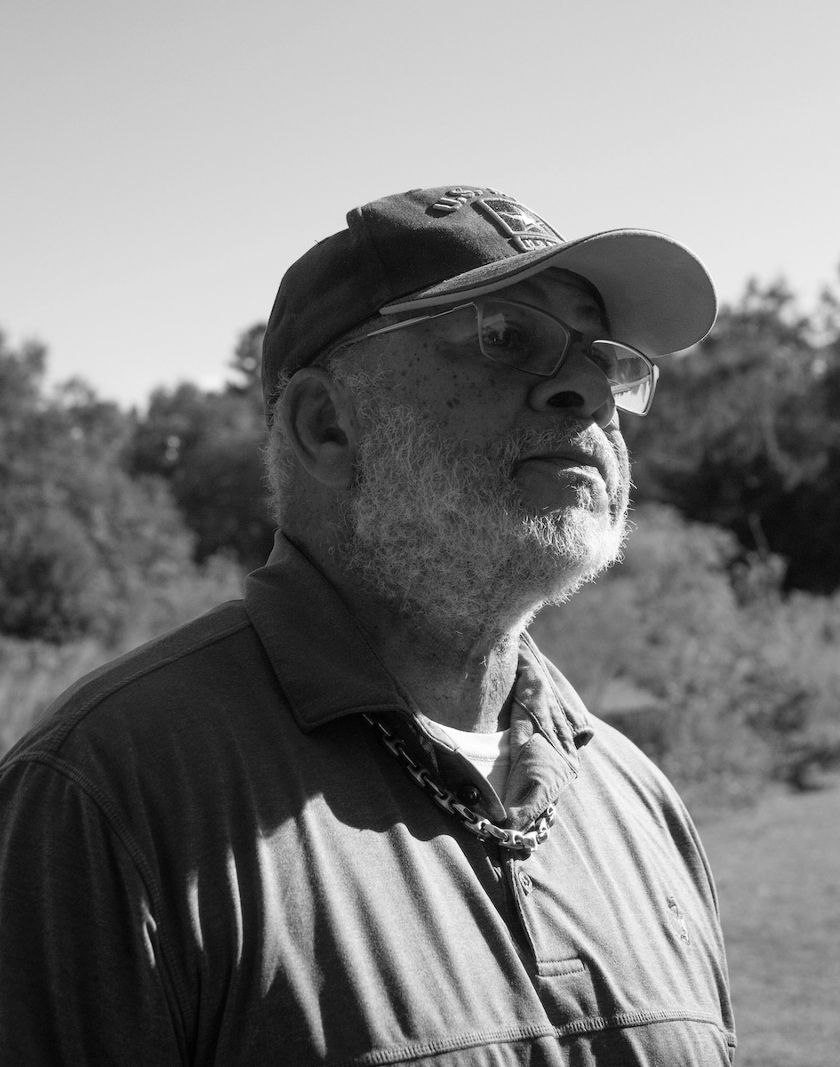A black and white image of James Siler, wearing glasses and a baseball cap