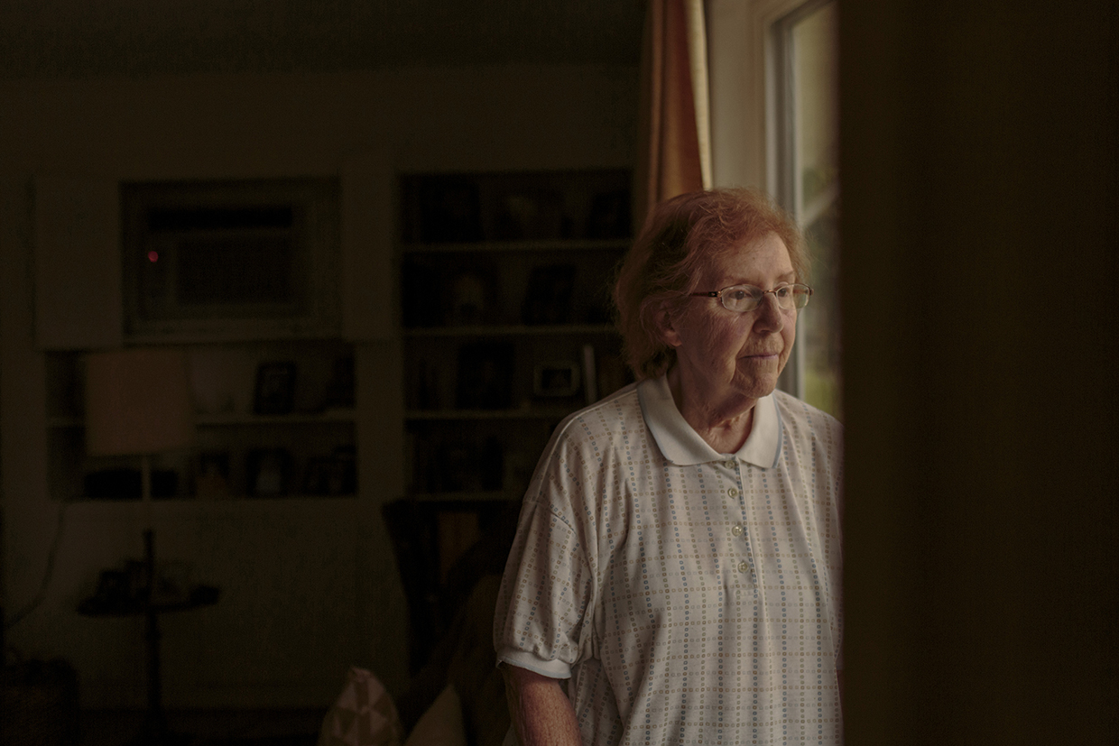 An elderly woman looking out of a window.