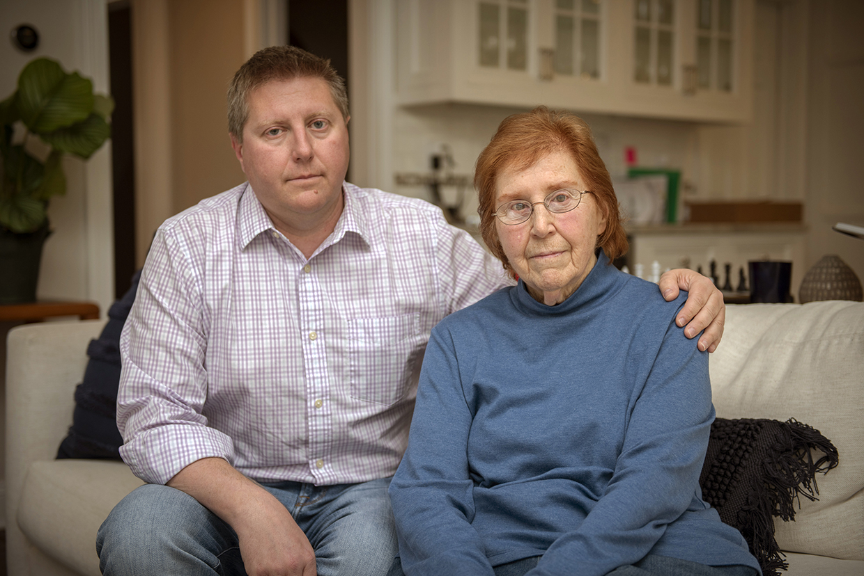 A photo of a middle-aged man and an older woman next to him sitting on a couch.