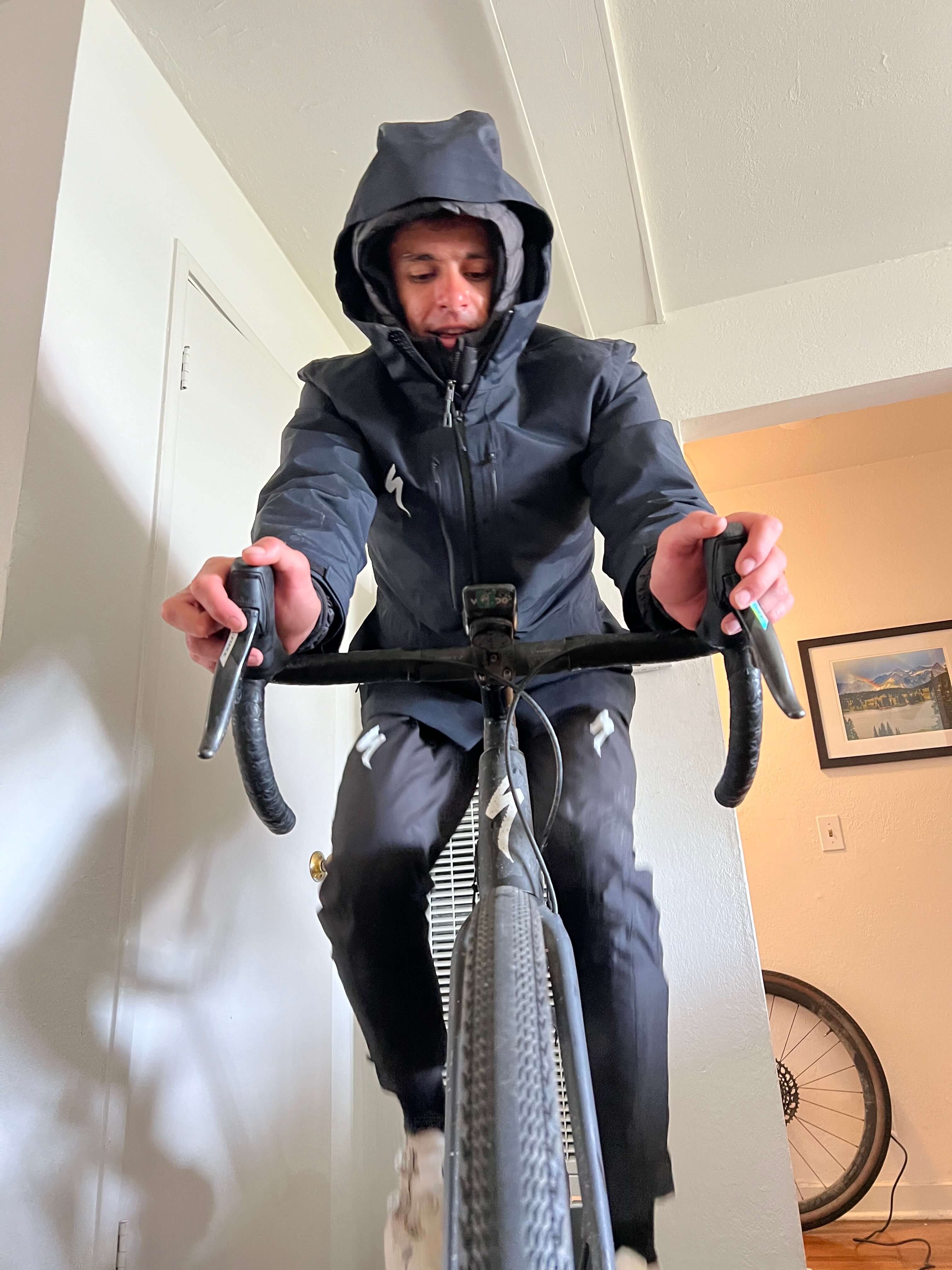 Photo showing cyclist Christopher Blevins training for the heat indoors, wearing layers of jackets.