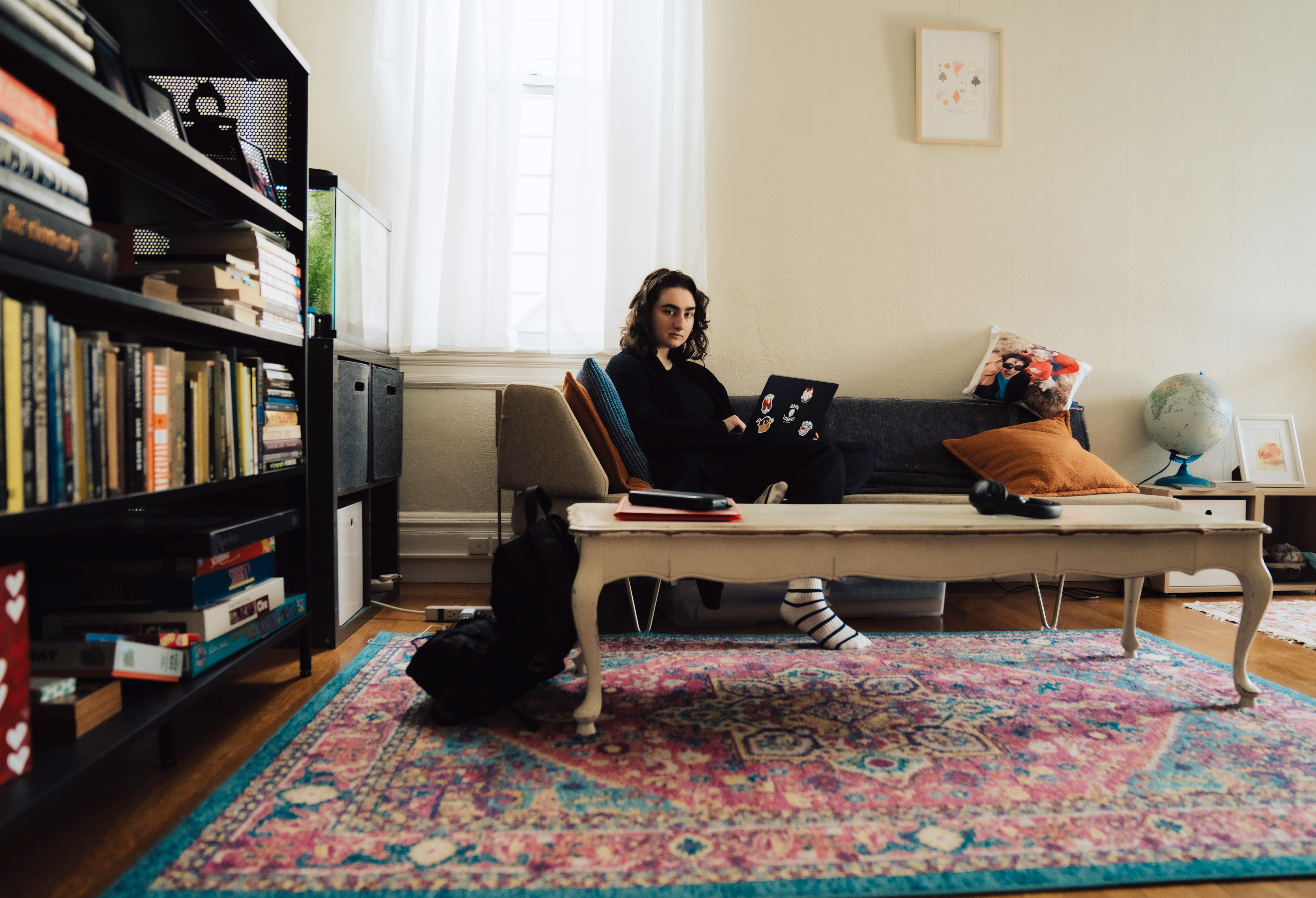 Aya Williams sitting down on a couch in a family living room with a laptop.
