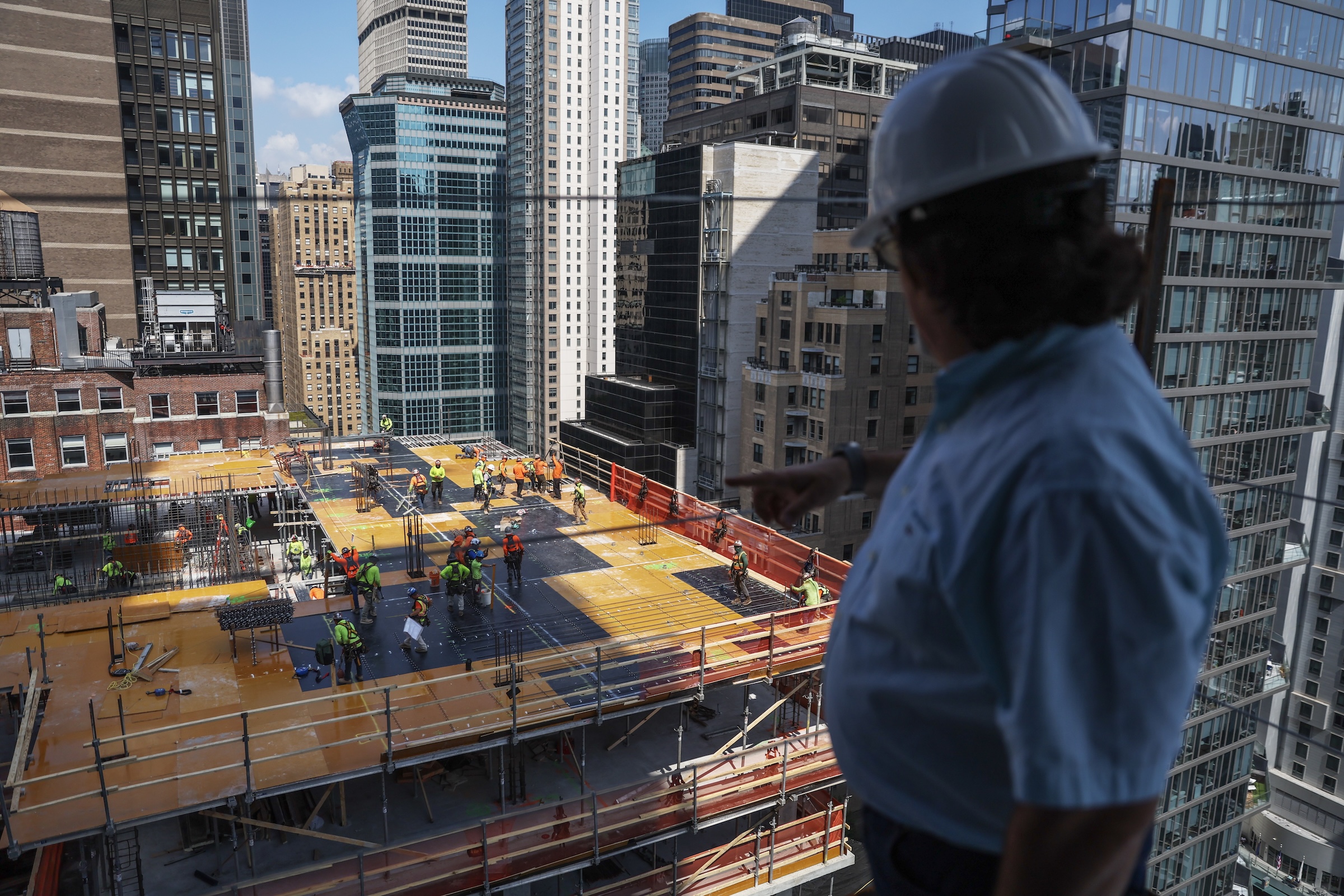 A man, wearing a hard hat and collared shirt, overlooks construction from the former Pfizer building tower.