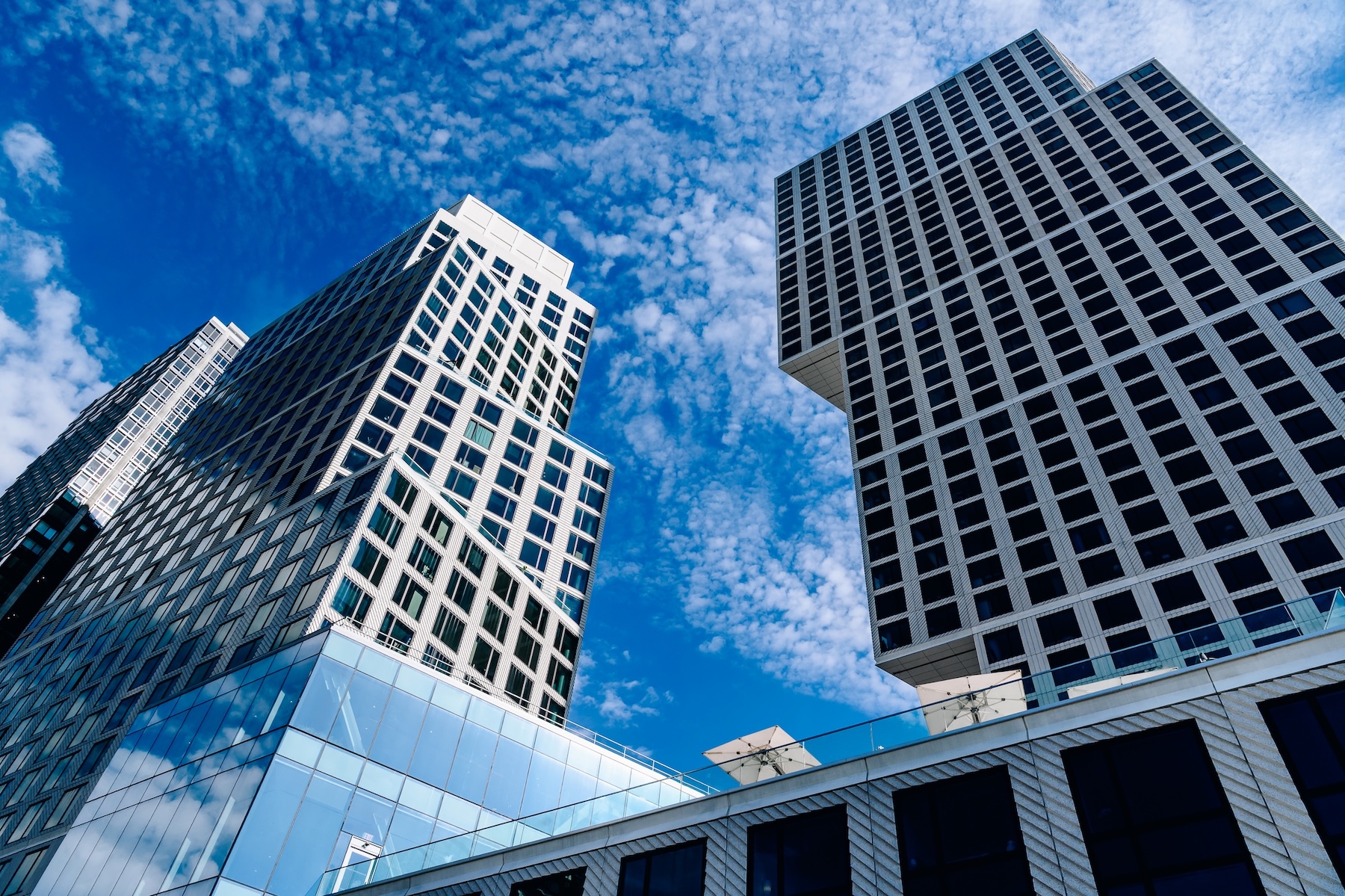 Two residential towers in Greenpoint, built in a geometric style contrast a bright blue sky.