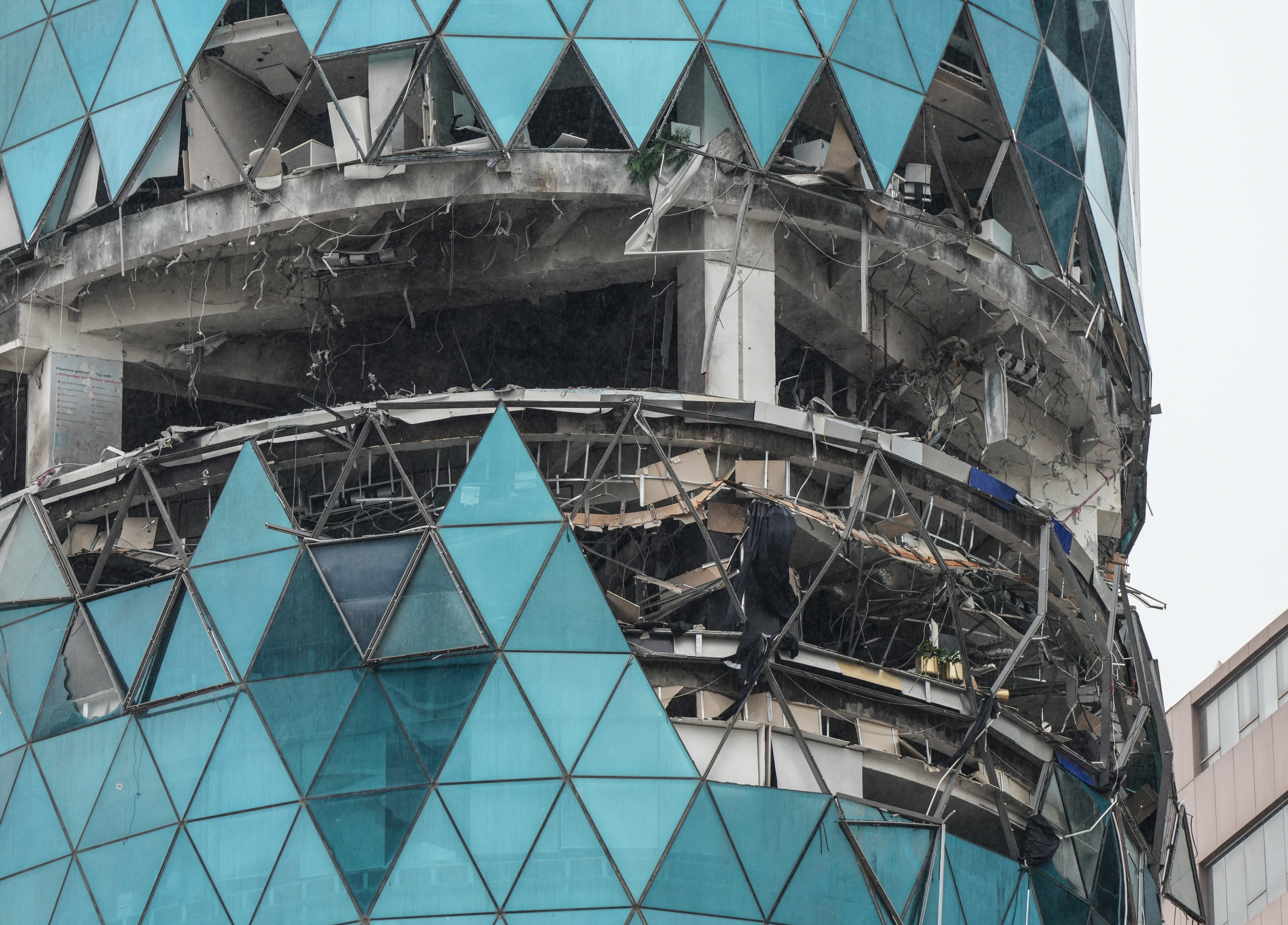 A section of a building is open and damaged floors are seen through the missing panes of glass.